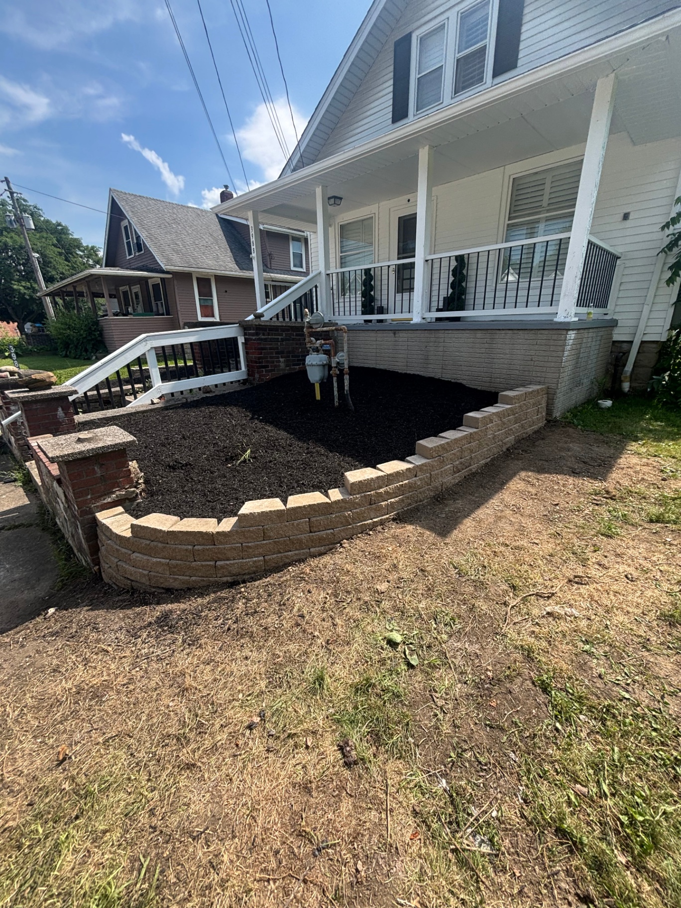 Custom stone retaining wall with fresh mulch bed along a front porch