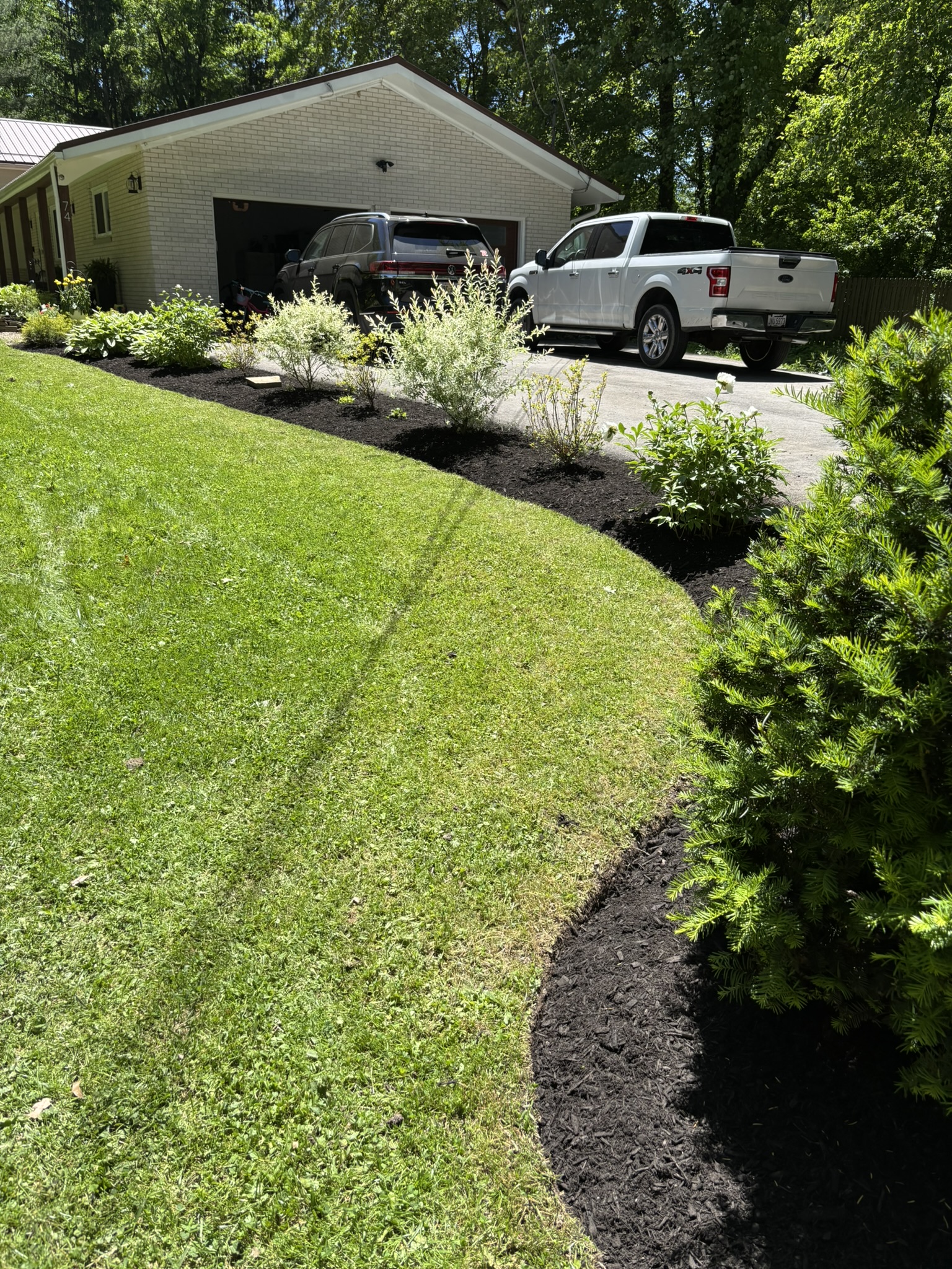 Curved mulch bed edging a manicured lawn beside a driveway