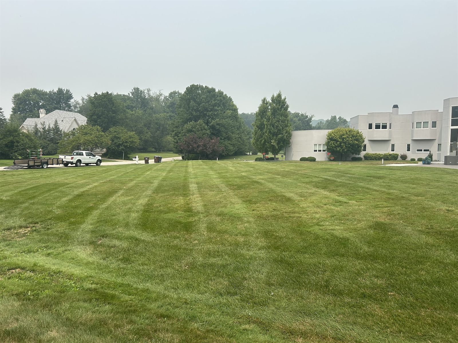 Big open lawn mowed in long stripes, with buildings at the far edge