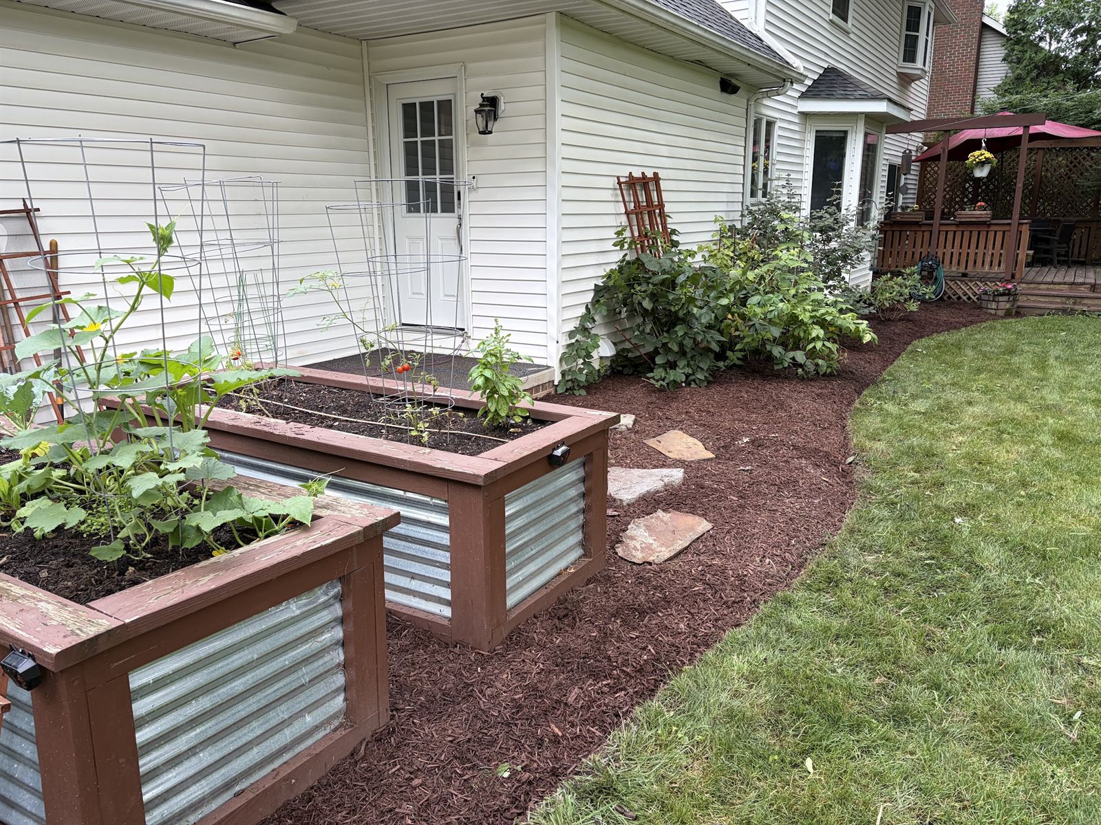 New raised planter boxes and a mulch bed beside a white house