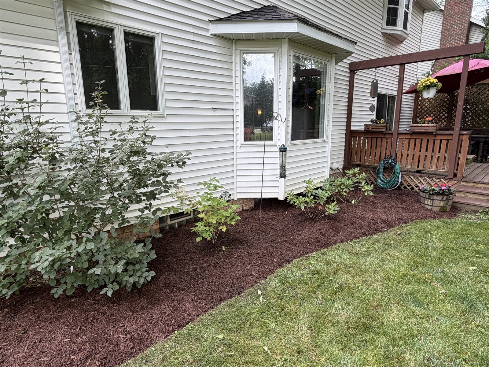 Fresh mulch beds and shrubs along a white house