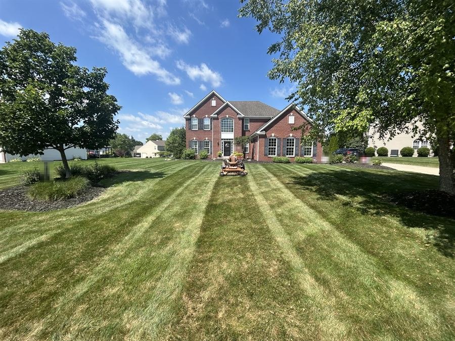 Sample photo: a big front lawn mowed in sharp stripes up to a brick house